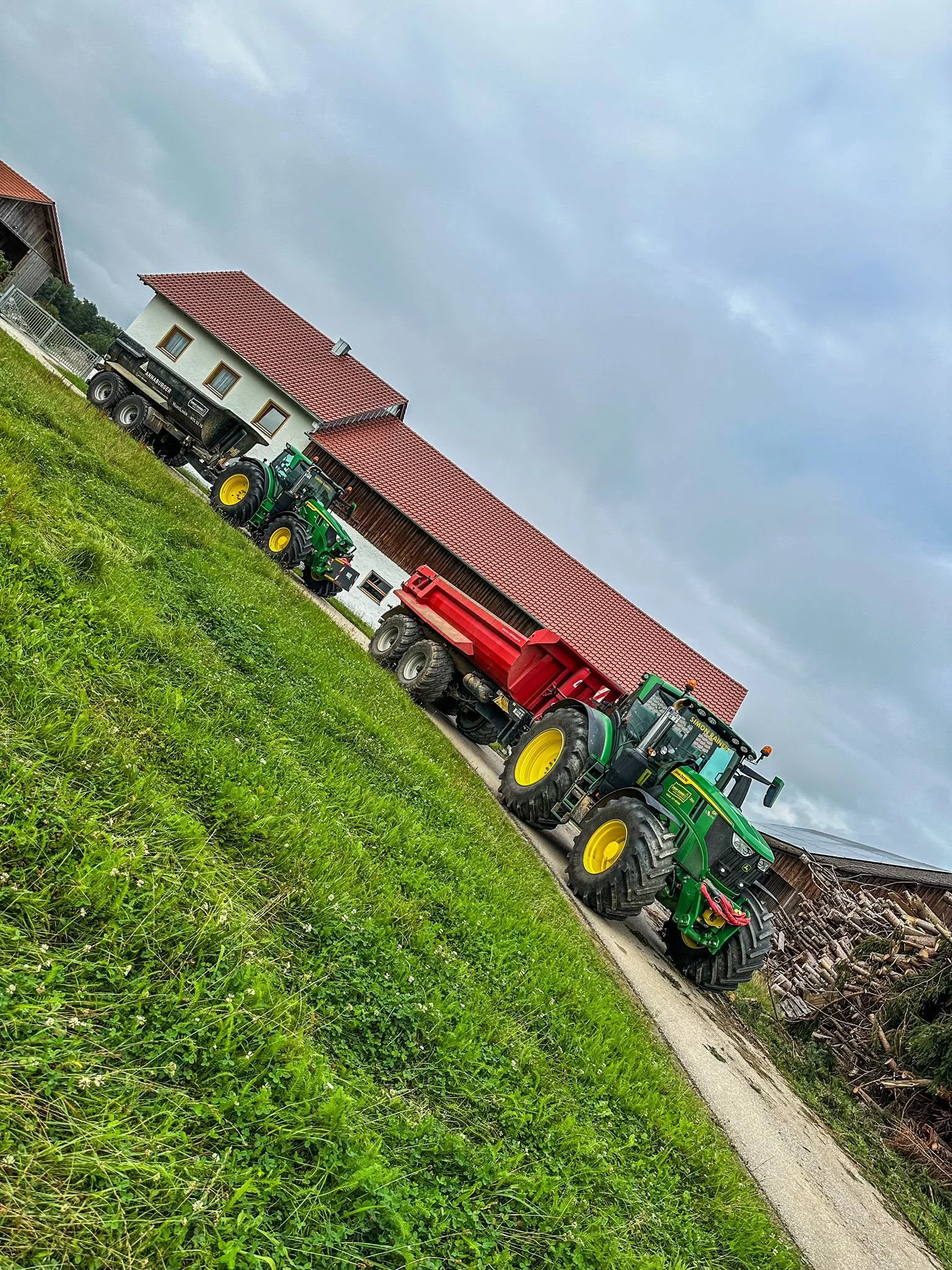 Zwei John-Deere-Traktoren mit schwarzer und roter Erdmulde auf dem Hof