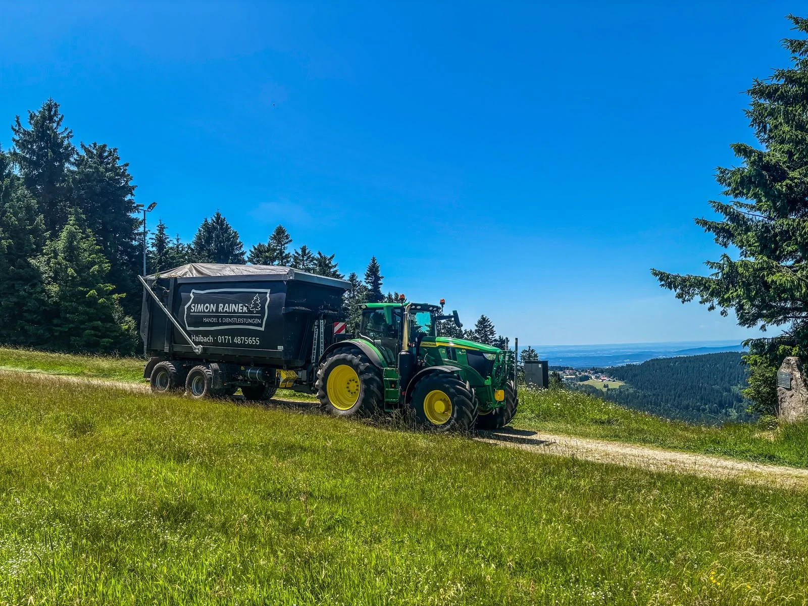 John-Deere-Traktor mit Hakenlift und schwarzem Container