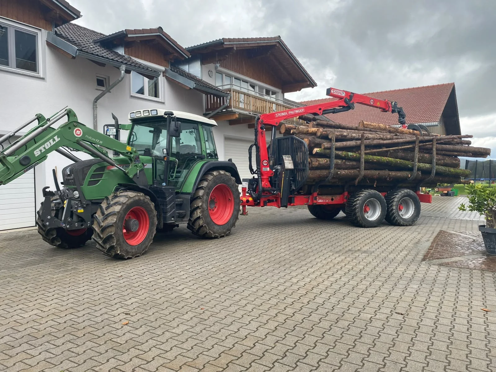Fendt-Traktor mit holzbeladenem Rückewagen und rotem Ladekran