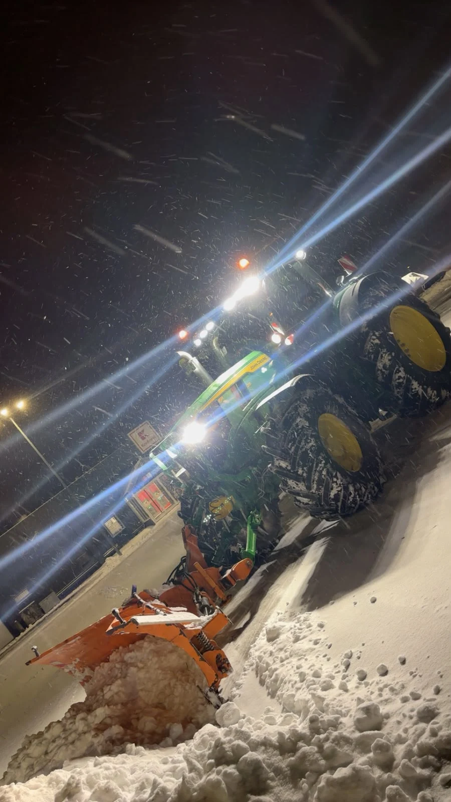 John-Deere-Traktor mit Schneepflug beim nächtlichen Winterdienst